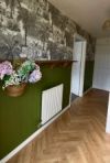 brown herringbone laminate in hallway with green panelling and monochrome wallpaper